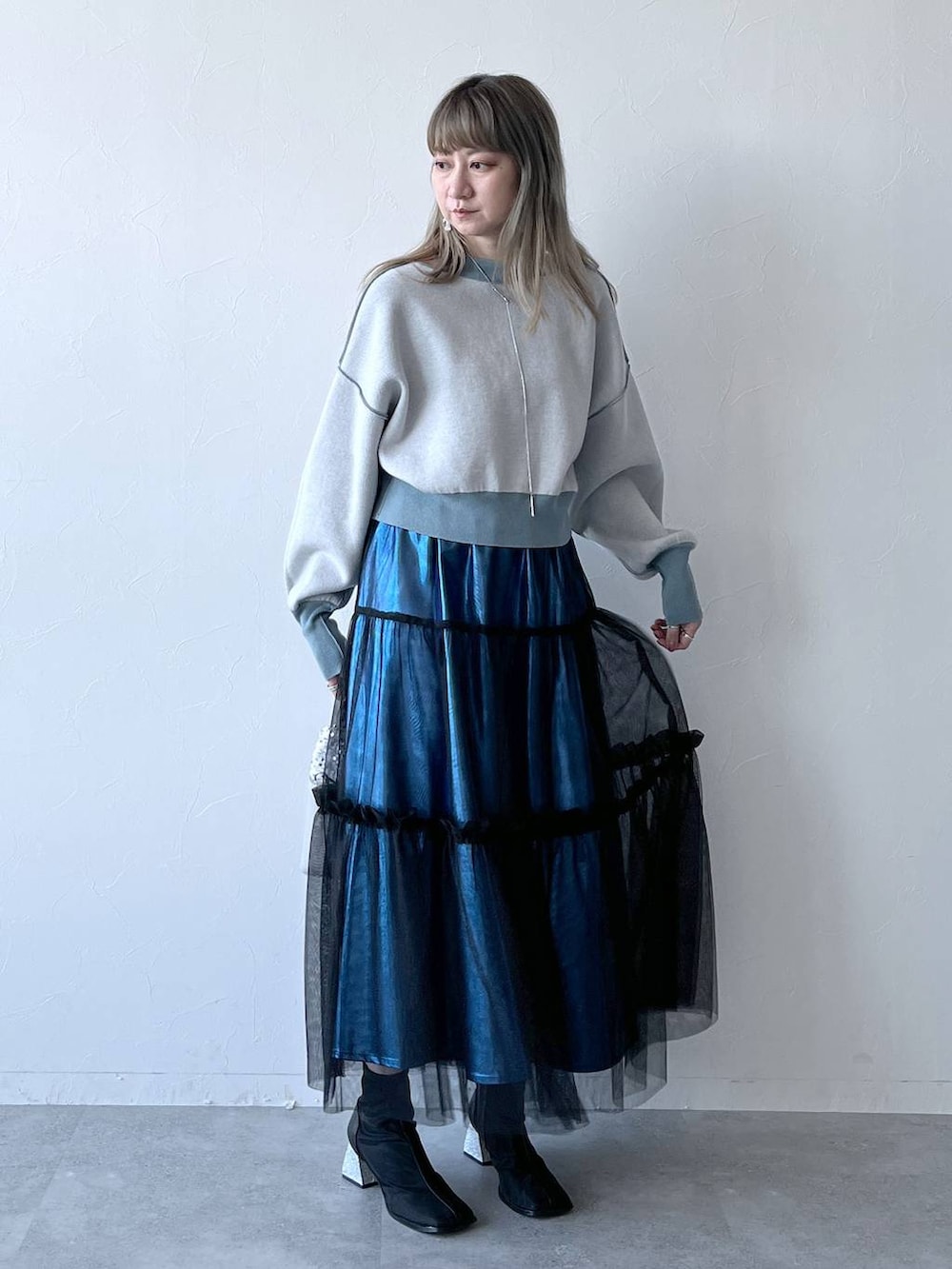 ブルー系のカーディガン/ボレロ、ブルー系のスカート、ホワイト系のショルダーバッグを着用したレディースの冬コーディネートの2枚目の写真