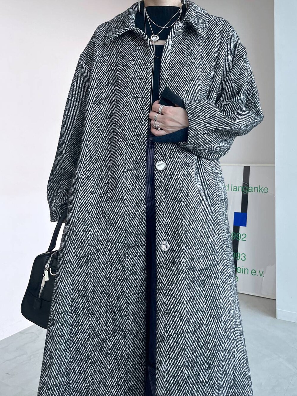 グレー系のステンカラーコート、ブラック系のボストンバッグ、シルバー系のブーツを着用したレディースの秋コーディネートの4枚目の写真