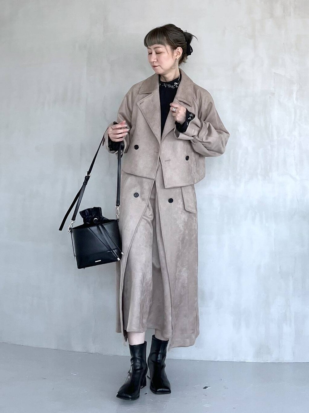 グレー系のブーツ、ブラック系のショルダーバッグ、ベージュ系のトレンチコートを着用したレディースの夏コーディネートの2枚目の写真