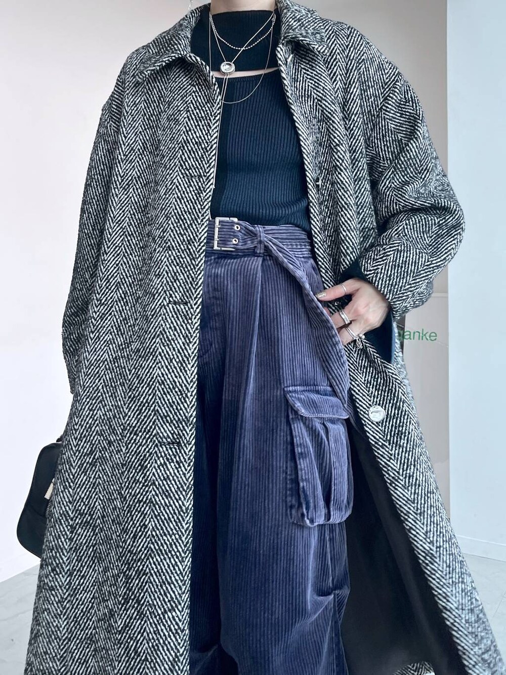 グレー系のステンカラーコート、ブラック系のボストンバッグ、シルバー系のブーツを着用したレディースの秋コーディネートの3枚目の写真