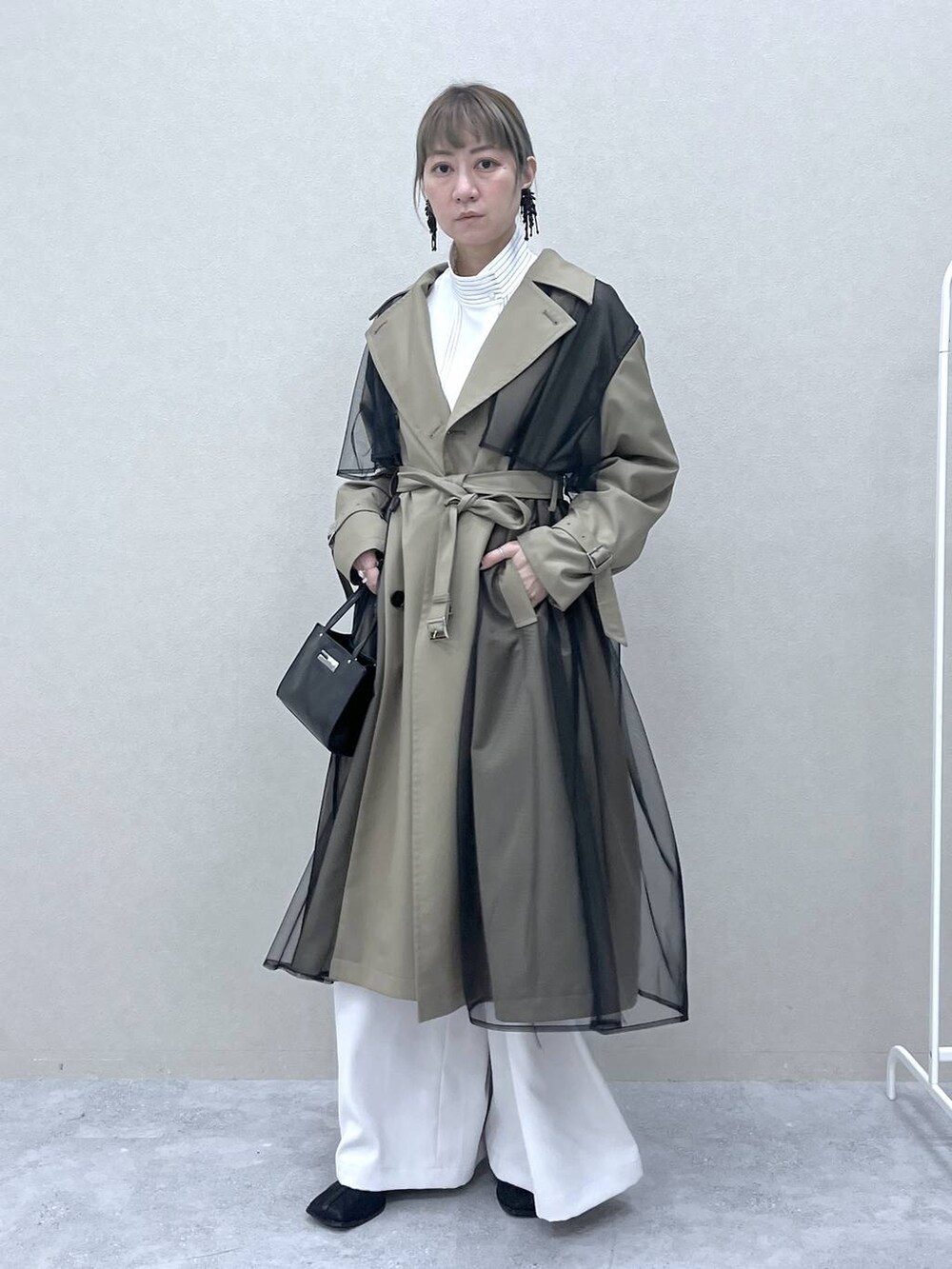ベージュ系のトレンチコート、ブラック系のショルダーバッグ、ホワイト系のシャツ/ブラウスを着用したレディースの冬コーディネートの6枚目の写真