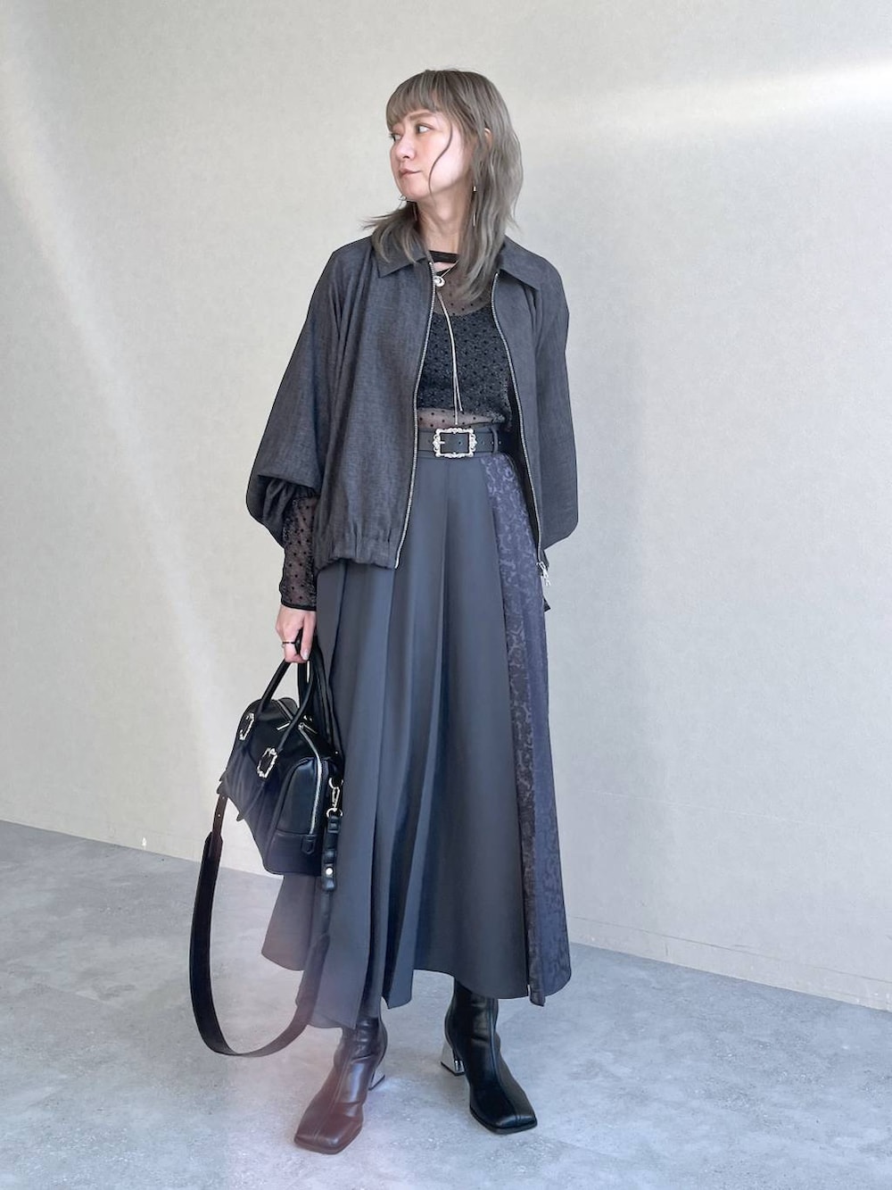 ブラック系のTシャツ/カットソー、ブラック系のボストンバッグ、ブラック系のブーツを着用したレディースの秋コーディネートの2枚目の写真