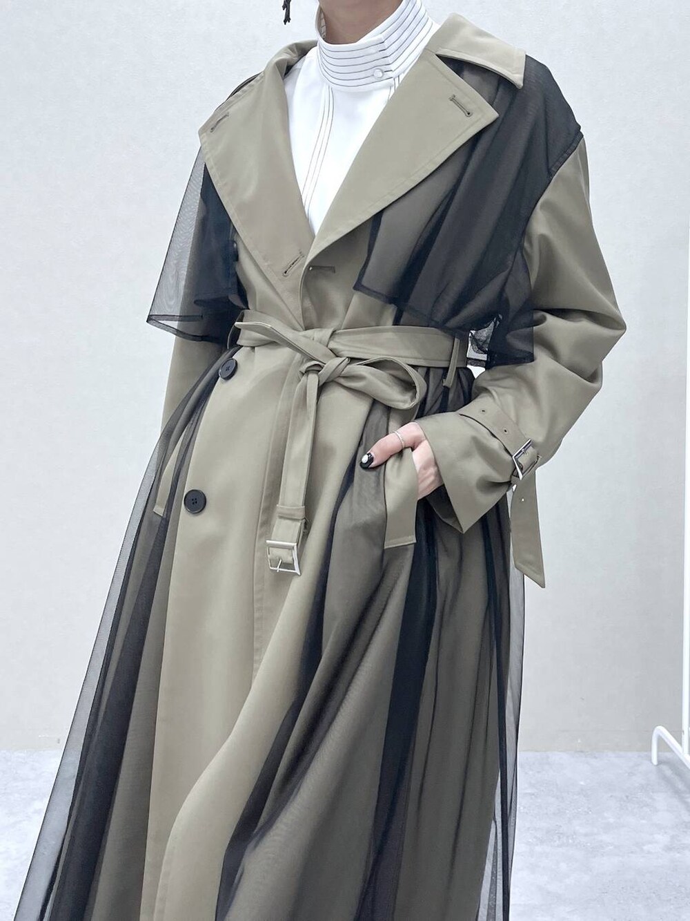 ベージュ系のトレンチコート、ブラック系のショルダーバッグ、ホワイト系のシャツ/ブラウスを着用したレディースの冬コーディネートの3枚目の写真