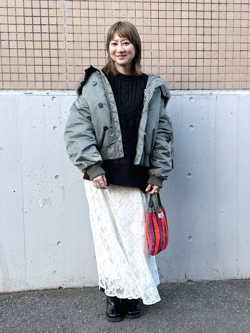 グリーン系のブルゾン、ブラック系のブーツ、ホワイト系のワンピースを着用したレディースの冬コーディネートの9枚目の写真