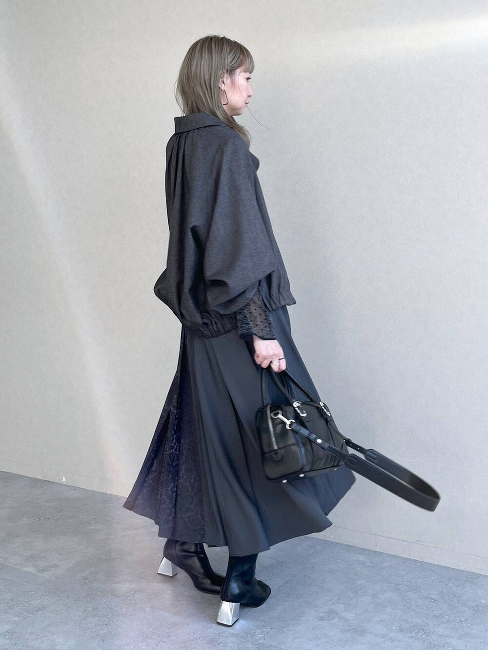 ブラック系のTシャツ/カットソー、ブラック系のボストンバッグ、ブラック系のブーツを着用したレディースの秋コーディネートの7枚目の写真