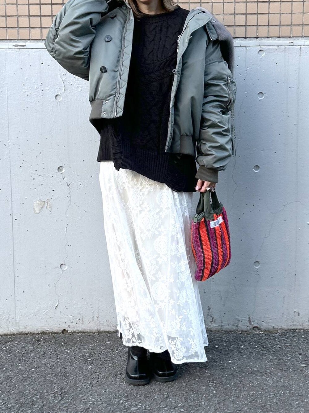 グリーン系のブルゾン、ブラック系のブーツ、ホワイト系のワンピースを着用したレディースの冬コーディネートの3枚目の写真