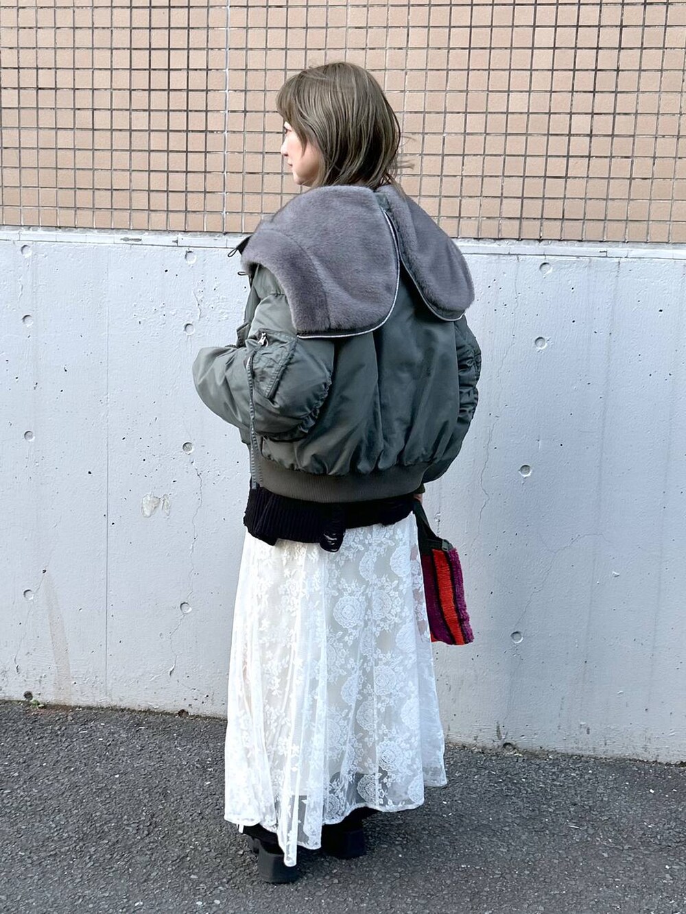 グリーン系のブルゾン、ブラック系のブーツ、ホワイト系のワンピースを着用したレディースの冬コーディネートの6枚目の写真