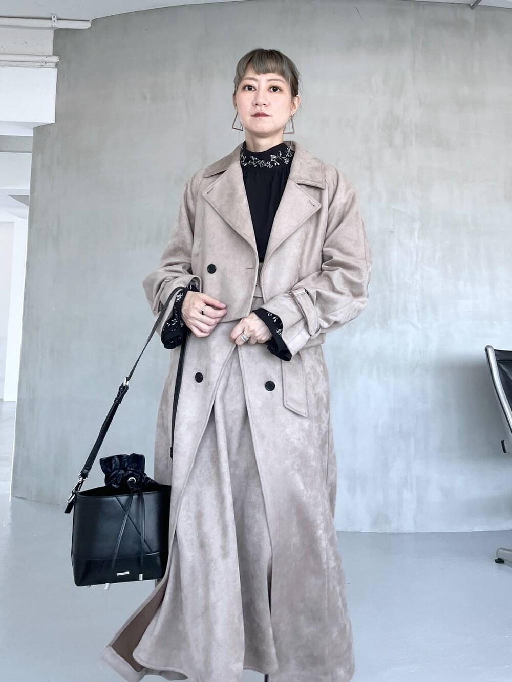 グレー系のブーツ、ブラック系のショルダーバッグ、ベージュ系のトレンチコートを着用したレディースの夏コーディネートの3枚目の写真