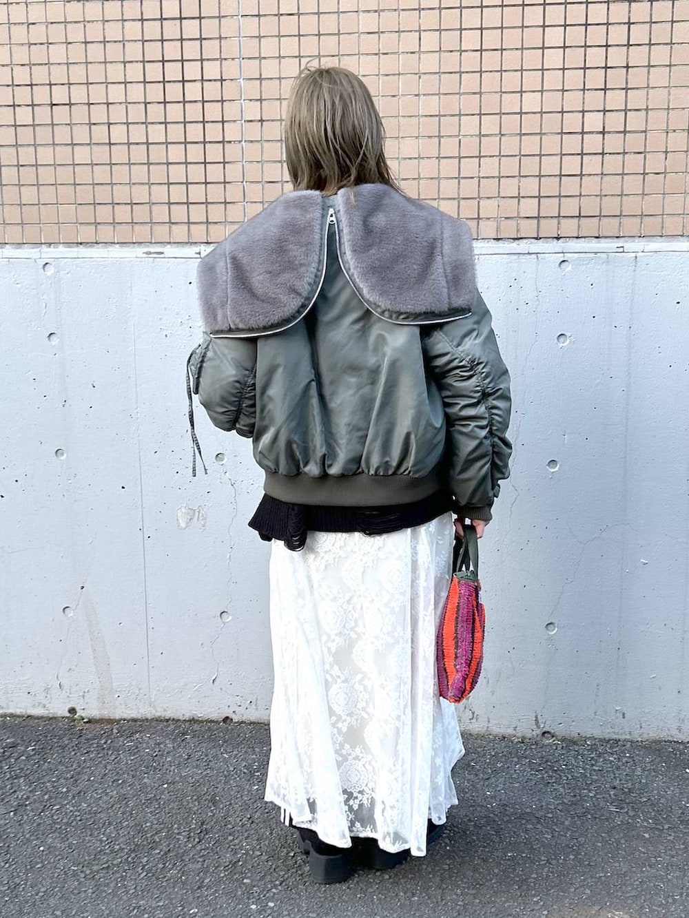 グリーン系のブルゾン、ブラック系のブーツ、ホワイト系のワンピースを着用したレディースの冬コーディネートの7枚目の写真