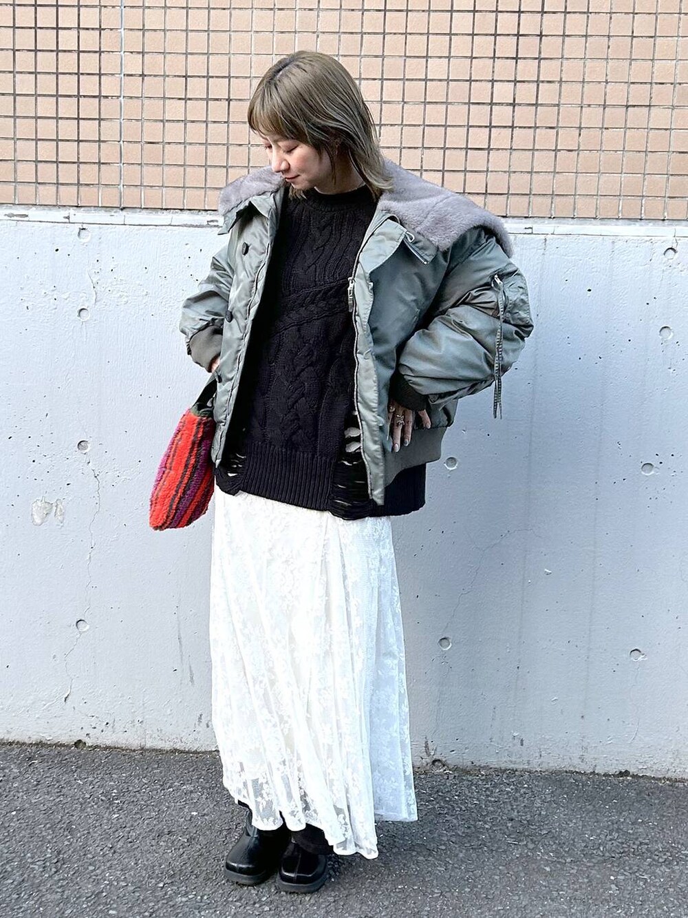 グリーン系のブルゾン、ブラック系のブーツ、ホワイト系のワンピースを着用したレディースの冬コーディネートの2枚目の写真