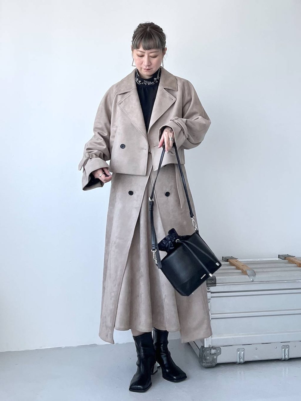 グレー系のブーツ、ブラック系のショルダーバッグ、ベージュ系のトレンチコートを着用したレディースの夏コーディネートの7枚目の写真