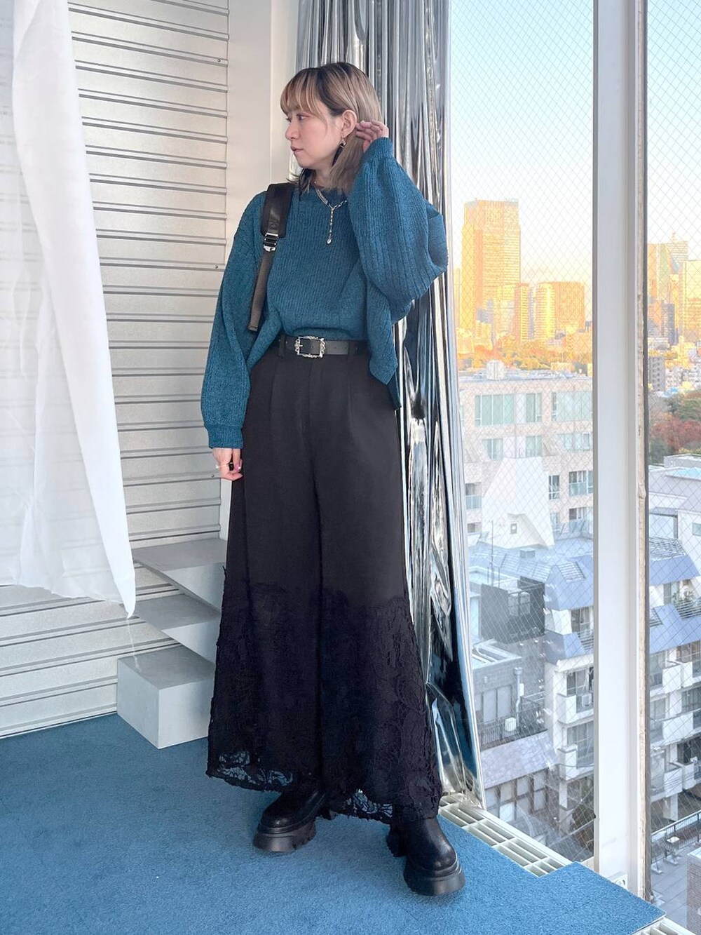 ブラック系のブーツ、ブルー系のニット/セーター、ブラック系のその他パンツを着用したレディースの冬コーディネートの2枚目の写真