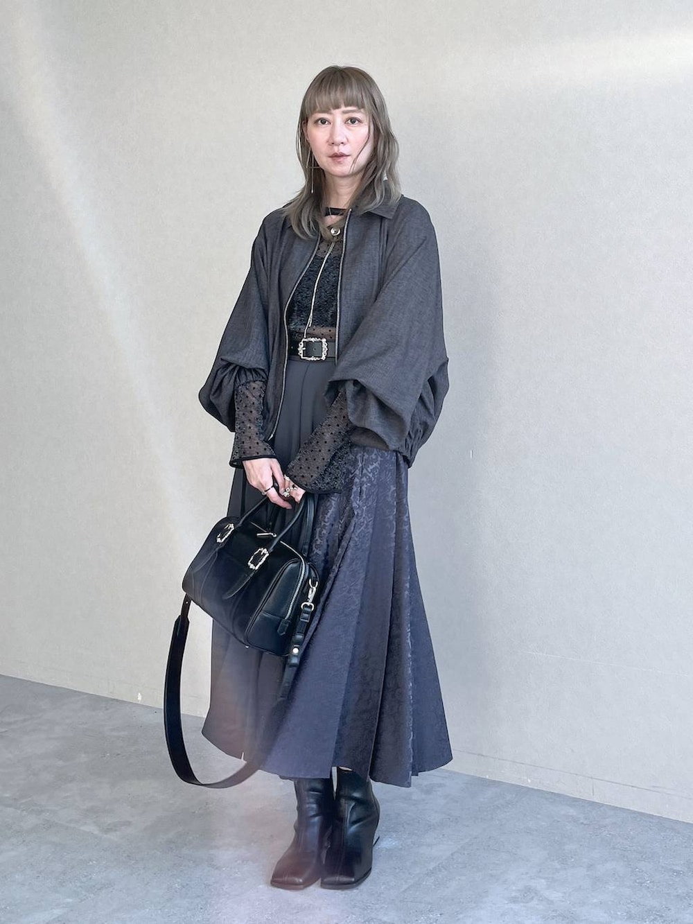 ブラック系のTシャツ/カットソー、ブラック系のボストンバッグ、ブラック系のブーツを着用したレディースの秋コーディネートの3枚目の写真