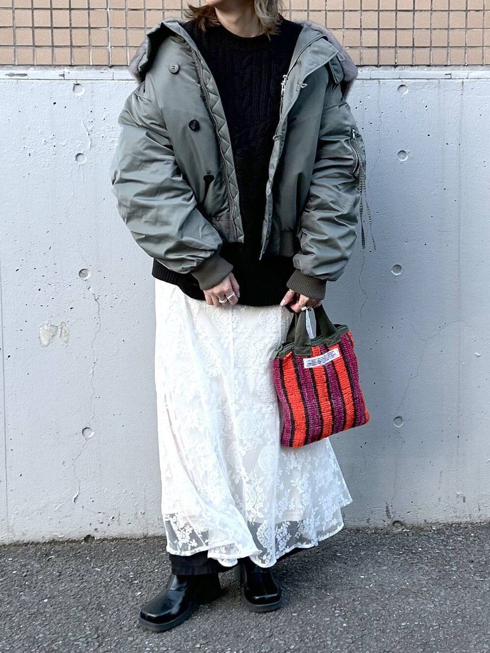 グリーン系のブルゾン、ブラック系のブーツ、ホワイト系のワンピースを着用したレディースの冬コーディネートの4枚目の写真