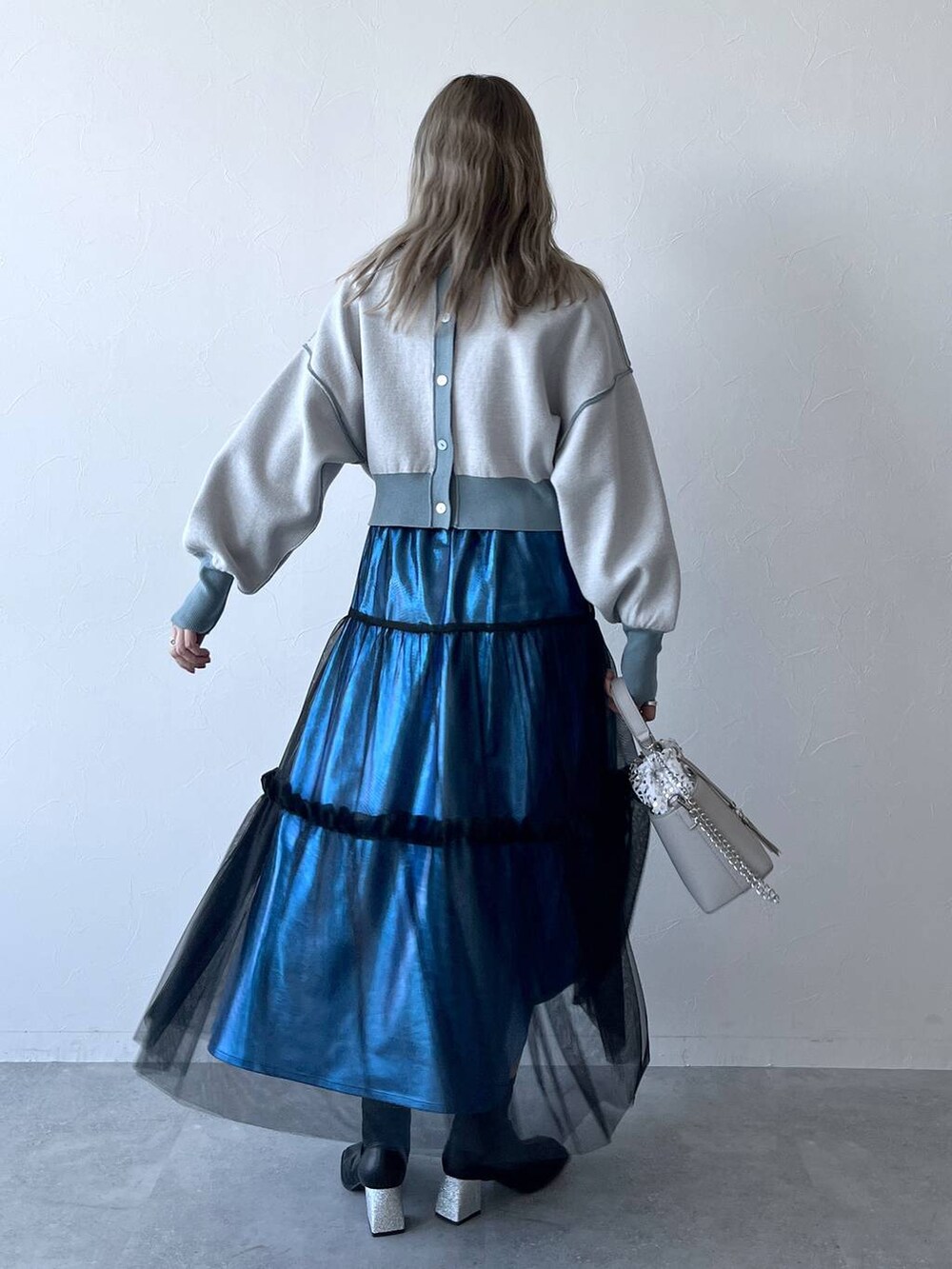 ブルー系のカーディガン/ボレロ、ブルー系のスカート、ホワイト系のショルダーバッグを着用したレディースの冬コーディネートの4枚目の写真