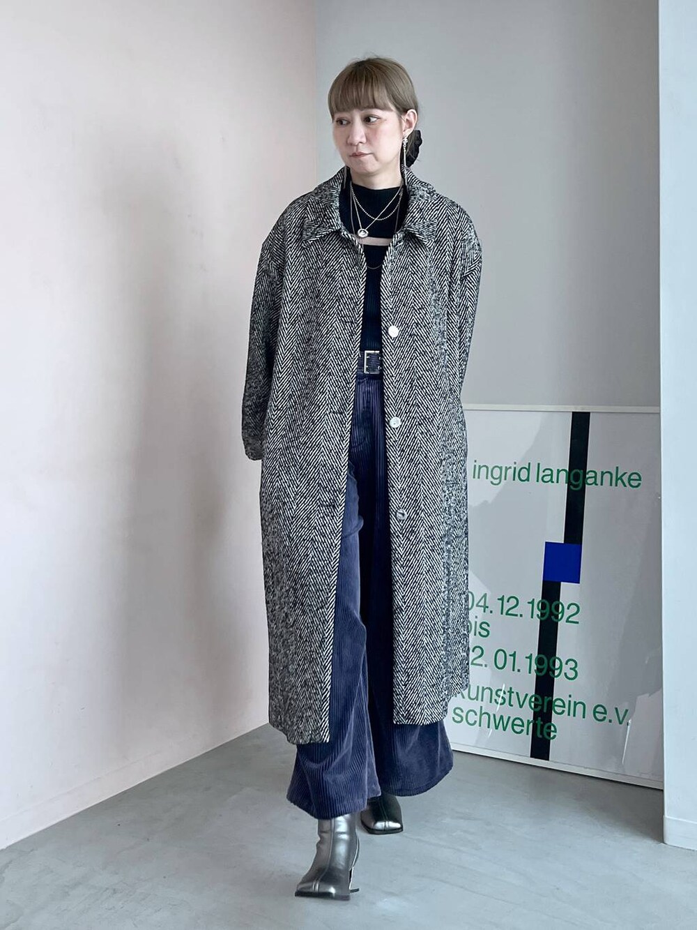 グレー系のステンカラーコート、ブラック系のボストンバッグ、シルバー系のブーツを着用したレディースの秋コーディネートの8枚目の写真