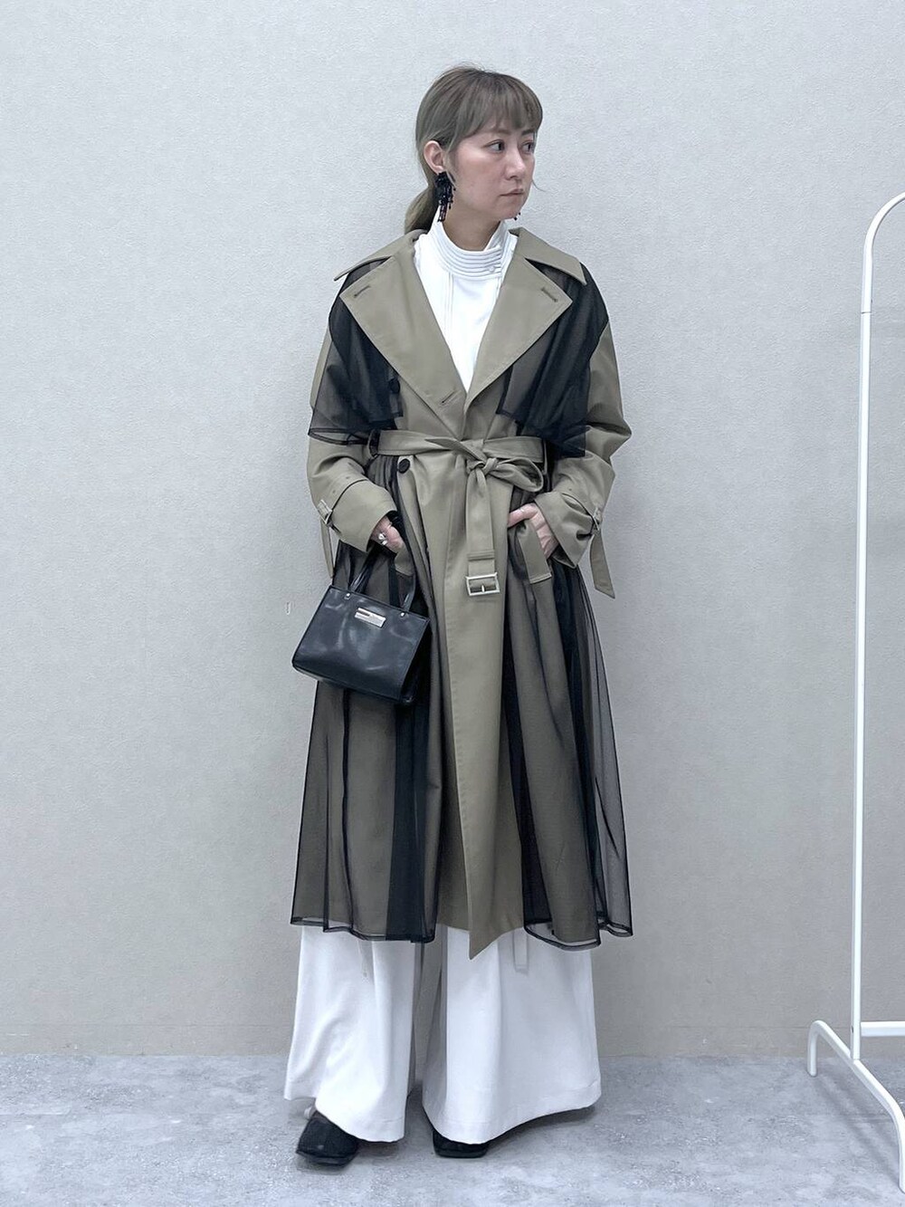 ベージュ系のトレンチコート、ブラック系のショルダーバッグ、ホワイト系のシャツ/ブラウスを着用したレディースの冬コーディネートの5枚目の写真