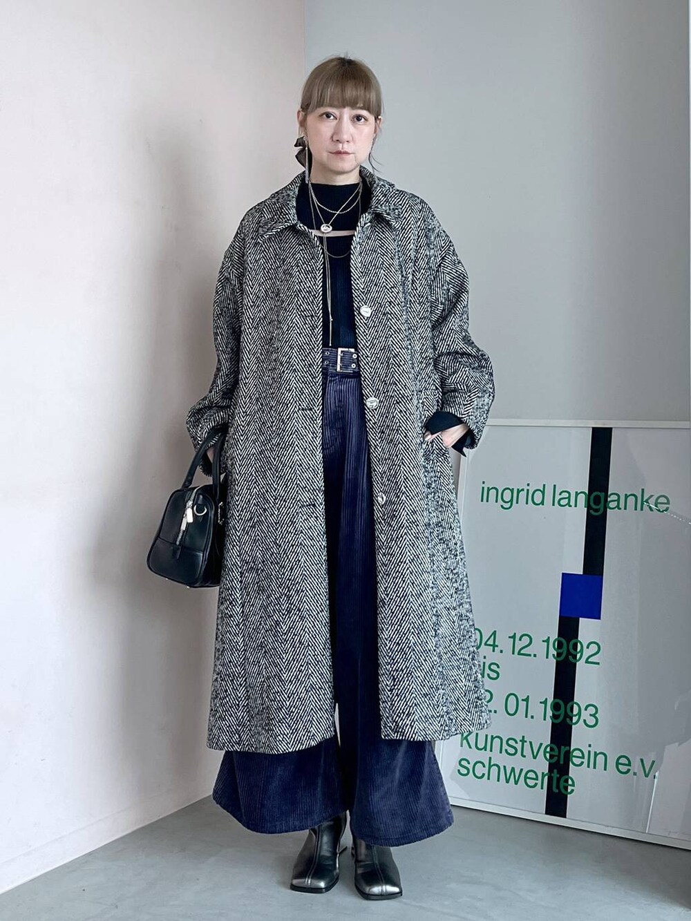 グレー系のステンカラーコート、ブラック系のボストンバッグ、シルバー系のブーツを着用したレディースの秋コーディネートの6枚目の写真