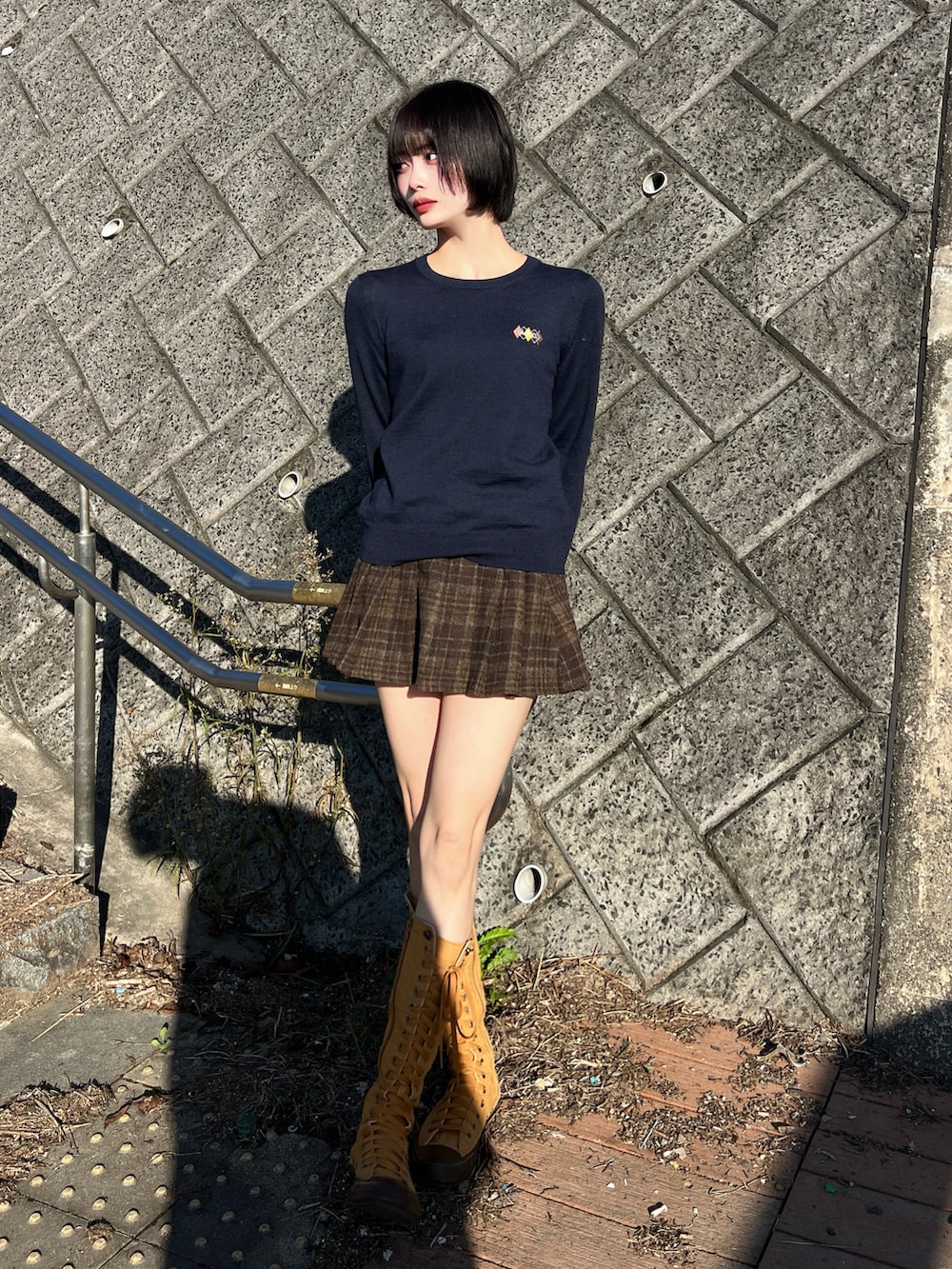 ブルー系のニット/セーター、ブラウン系のスカート、ブラウン系のブーツを着用したレディースの秋コーディネートの2枚目の写真