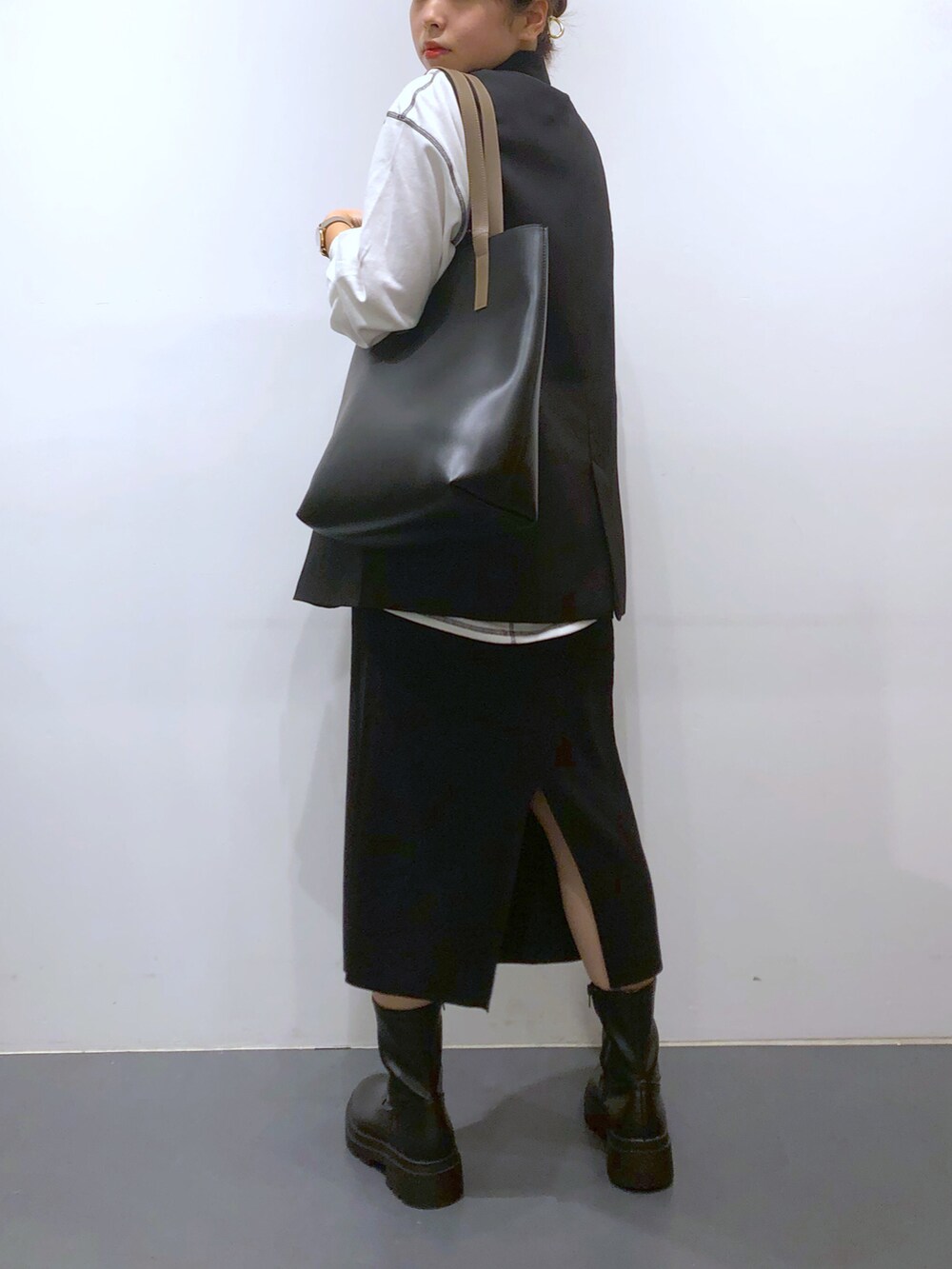 ブラック系のベスト、ホワイト系のTシャツ/カットソー、ブラック系のスカートを着用したレディースの秋コーディネートの2枚目の写真