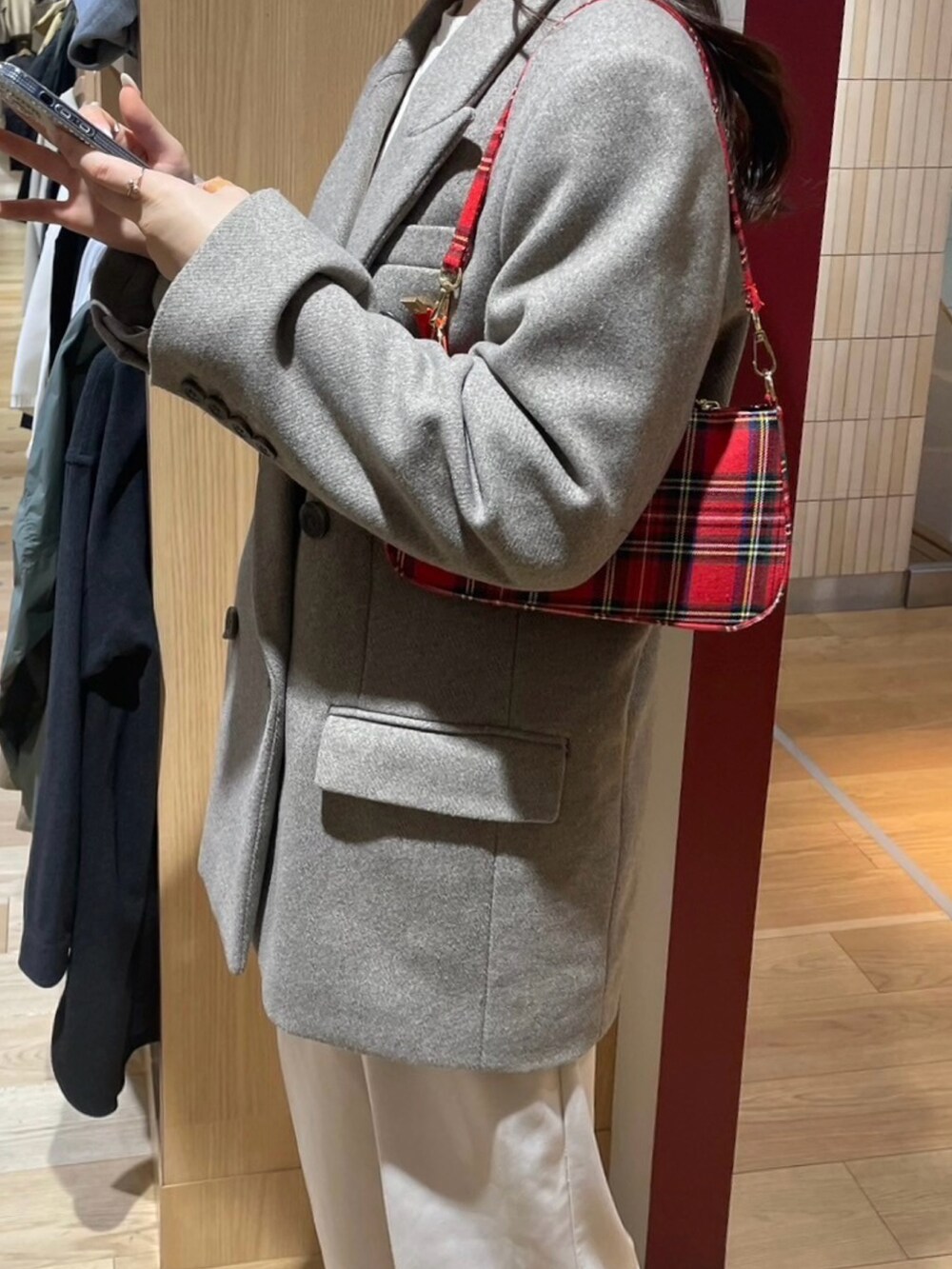 ベージュ系のテーラードジャケット、レッド系のハンドバッグ、ホワイト系のスラックスを着用したレディースの冬コーディネートの2枚目の写真