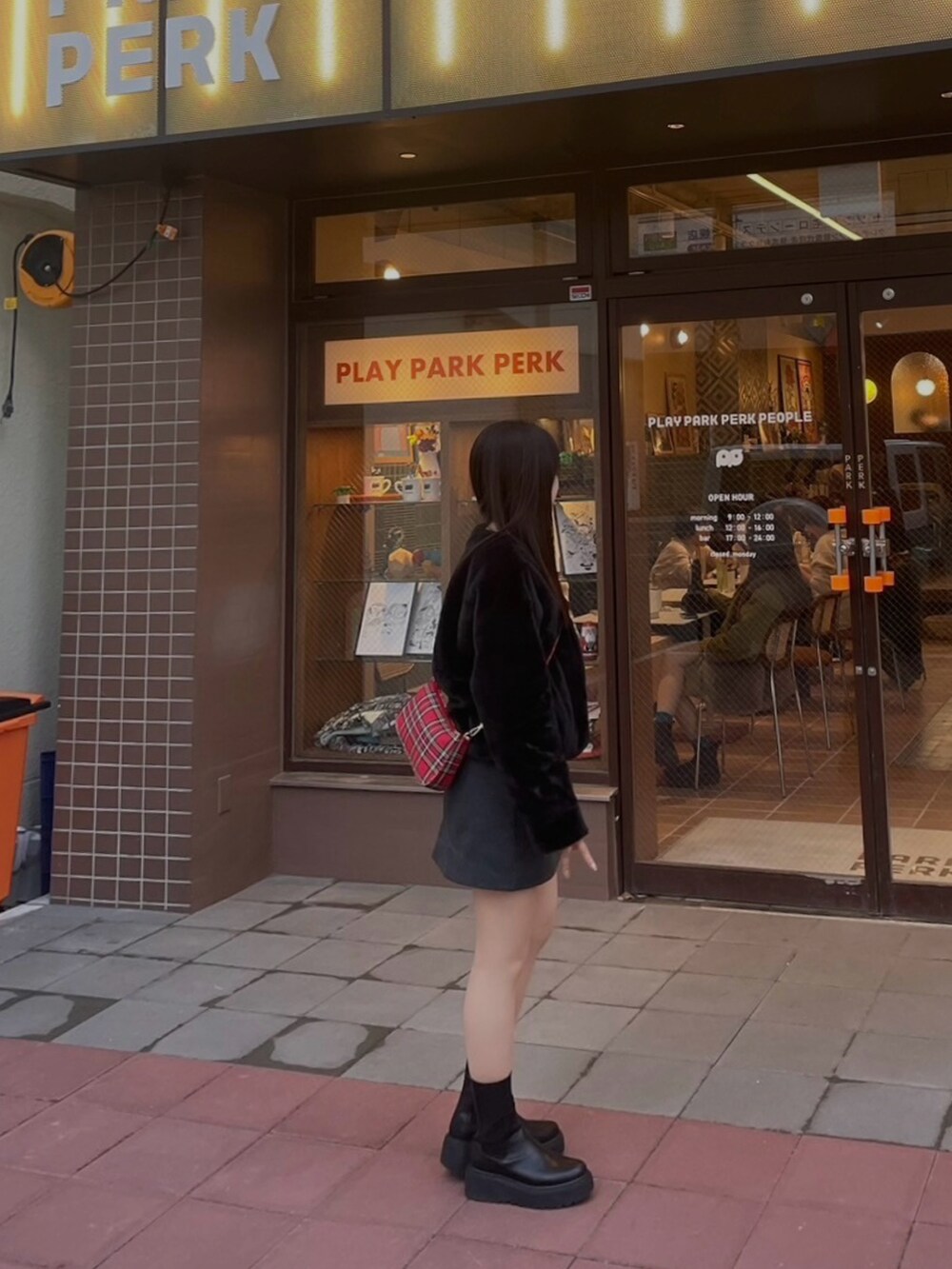 ブラック系のブーツ、レッド系のハンドバッグ、グレー系のスカートを着用したレディースの冬コーディネートの2枚目の写真