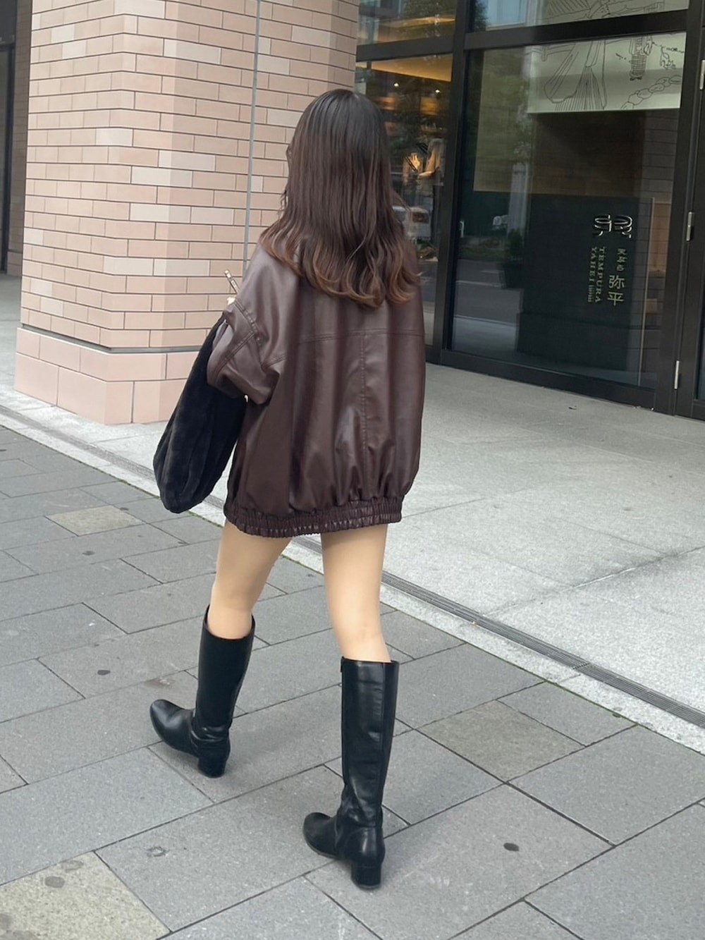 ブラウン系のブルゾン、ブラック系のブーツ、ブラック系のトートバッグを着用したレディースの秋コーディネートの2枚目の写真