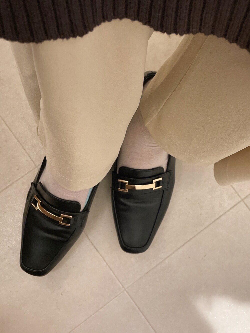 ブラック系のローファー、ブラウン系のワンピース、ホワイト系のスラックスを着用したレディースの冬コーディネートの2枚目の写真