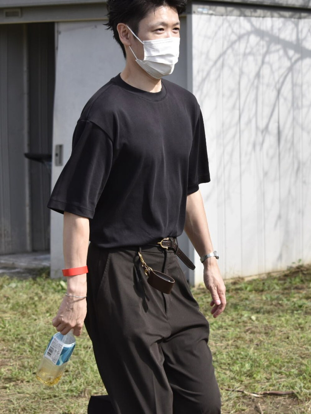 ブラック系のTシャツ/カットソー、ブラウン系のスラックス、グレー系のスニーカーを着用したメンズの秋コーディネートの3枚目の写真