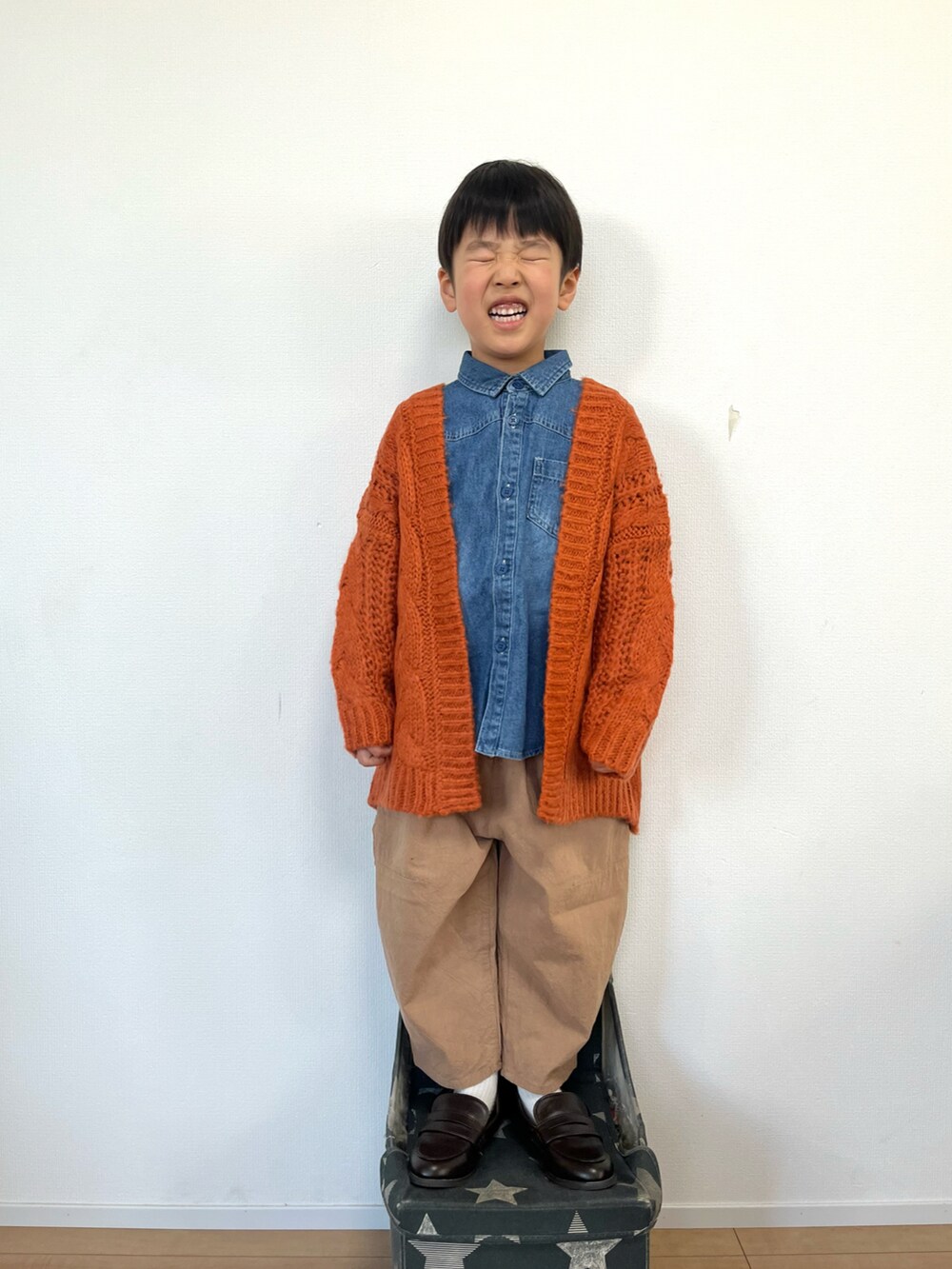 オレンジ系のカーディガン/ボレロ、ブルー系のシャツ/ブラウス、ベージュ系のパンツを着用したキッズの冬コーディネートの2枚目の写真