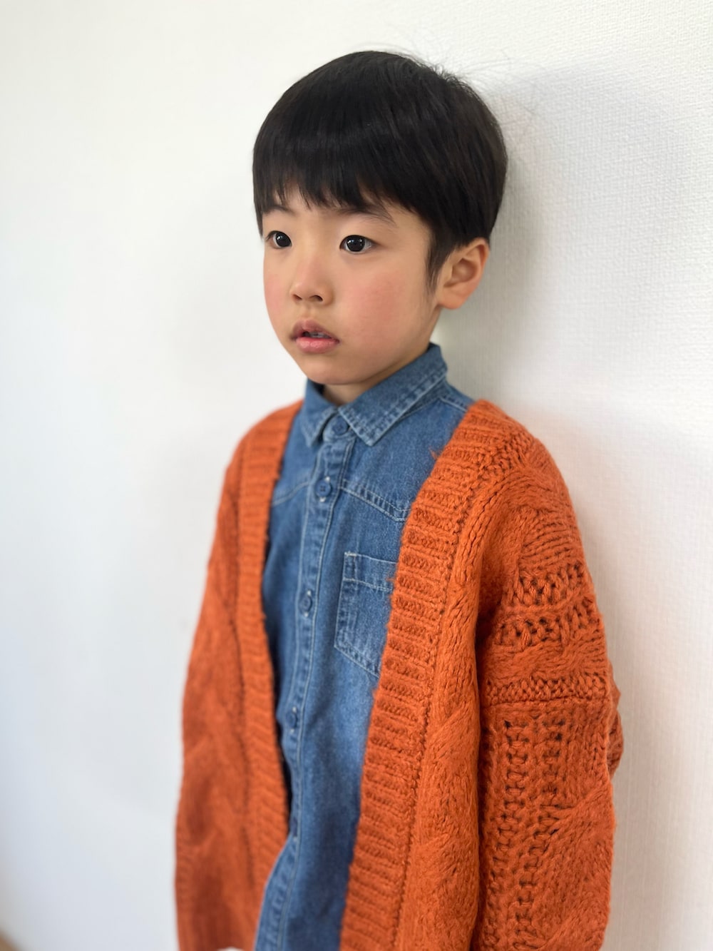 オレンジ系のカーディガン/ボレロ、ブルー系のシャツ/ブラウス、ベージュ系のパンツを着用したキッズの冬コーディネートの3枚目の写真