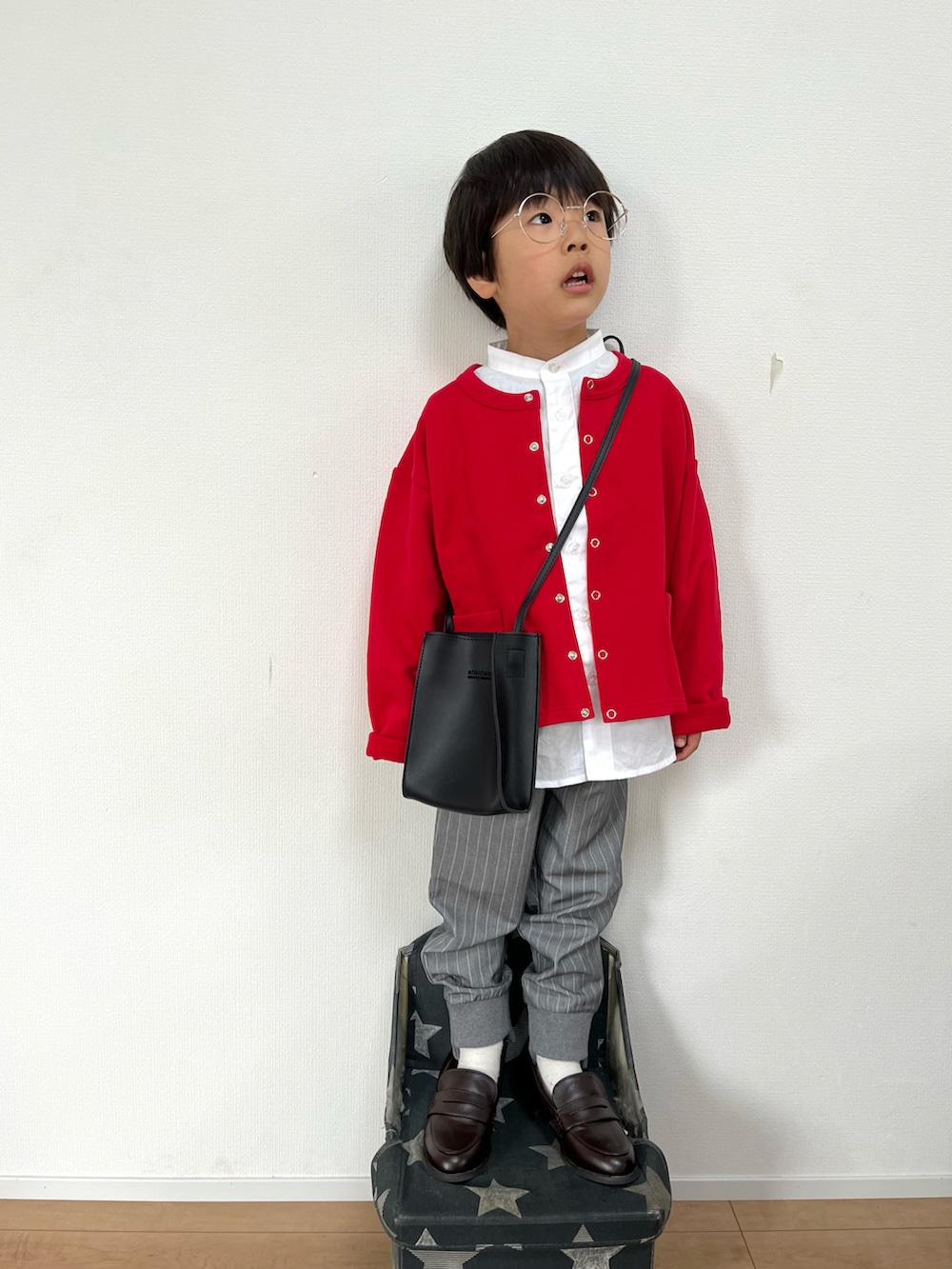 レッド系のカーディガン/ボレロ、ホワイト系のシャツ/ブラウス、ブラック系のショルダーバッグを着用したキッズの春コーディネートの2枚目の写真