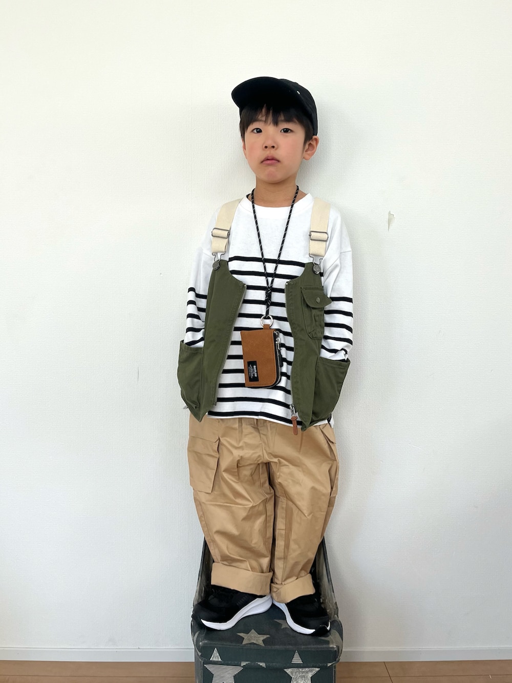 グリーン系のベスト、ホワイト系のTシャツ/カットソー、ベージュ系のカーゴパンツを着用したキッズの冬コーディネートの2枚目の写真