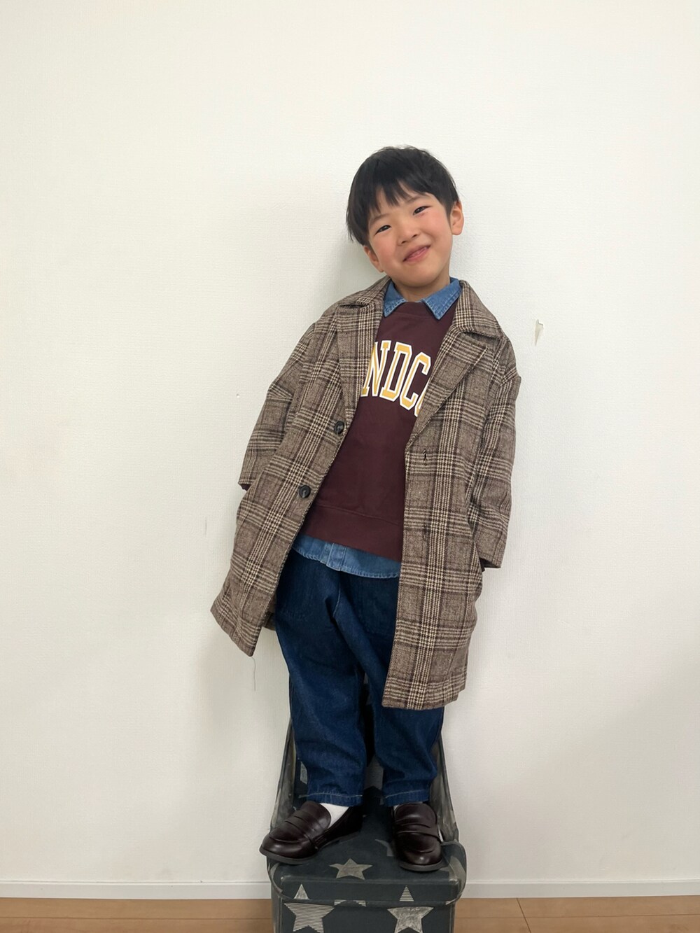 ブラウン系のチェスターコート、ブラウン系のスウェット、ブルー系のシャツ/ブラウスを着用したキッズの冬コーディネートの2枚目の写真