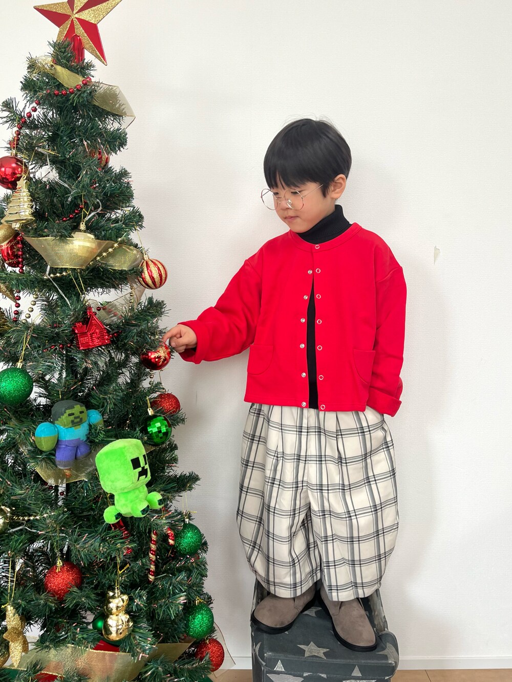 レッド系のカーディガン/ボレロ、ブラック系のニット/セーター、ホワイト系のその他パンツを着用したキッズの冬コーディネートの3枚目の写真