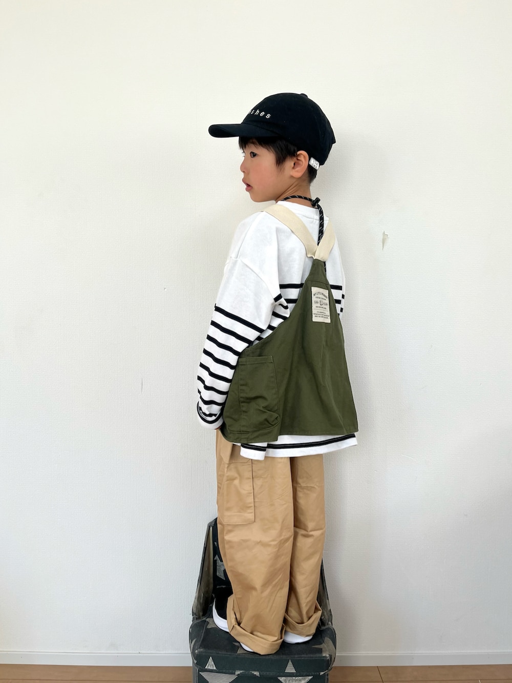 グリーン系のベスト、ホワイト系のTシャツ/カットソー、ベージュ系のカーゴパンツを着用したキッズの冬コーディネートの3枚目の写真