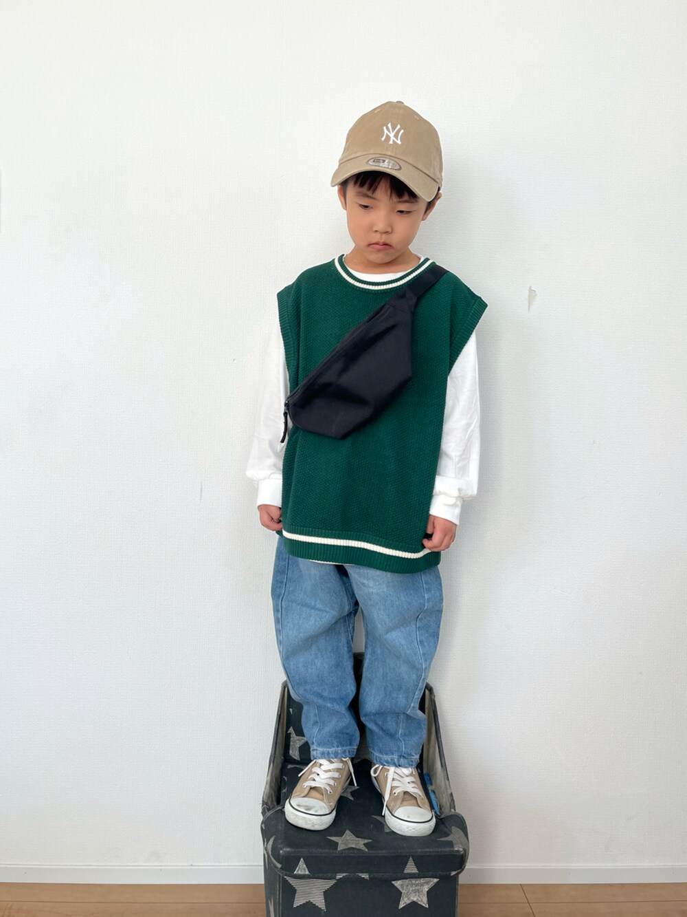 ブラック系のボディバッグ/ウエストポーチ、グリーン系のベスト、ブルー系のデニムパンツを着用したキッズの秋コーディネートの2枚目の写真