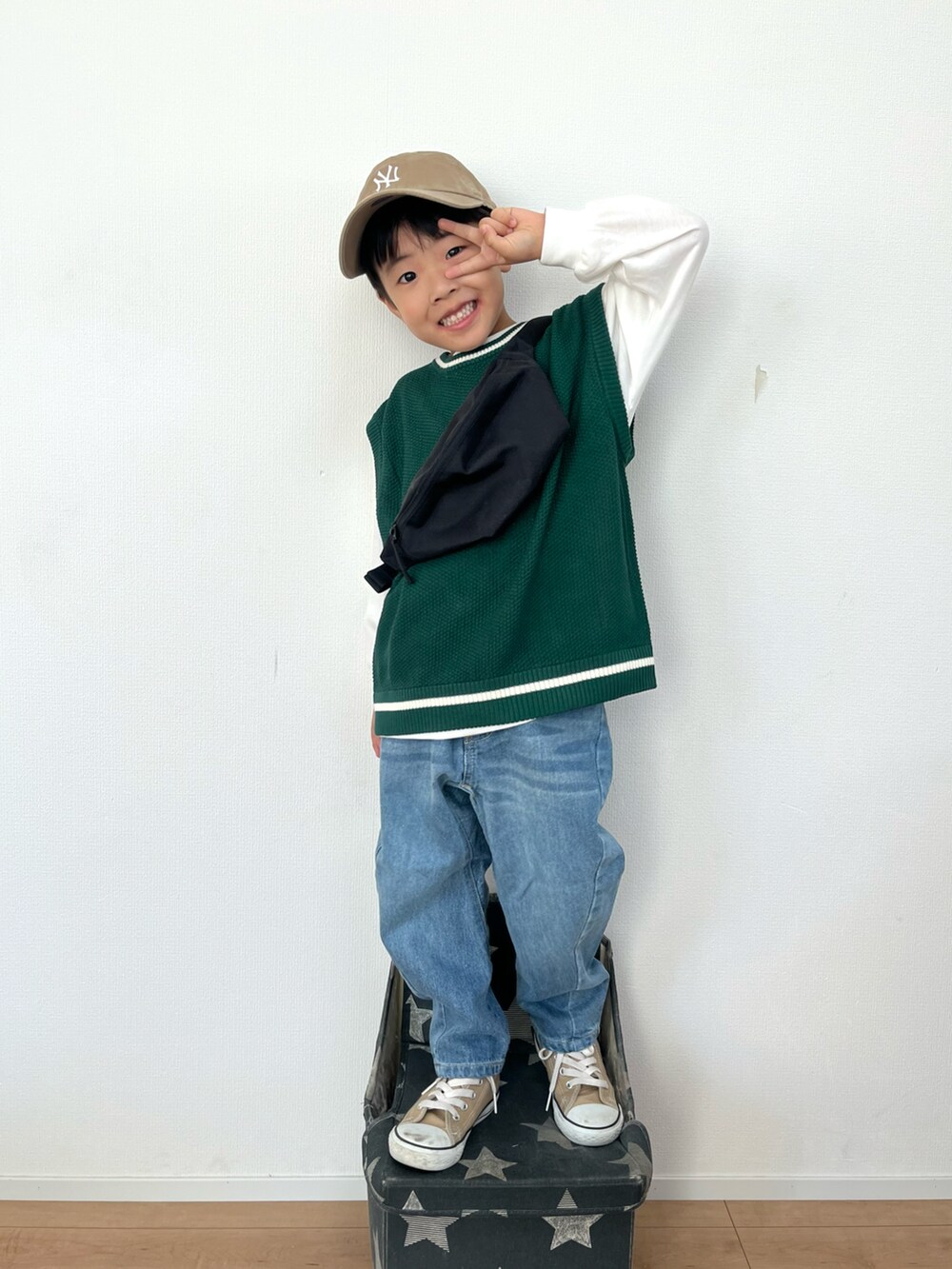 ブラック系のボディバッグ/ウエストポーチ、グリーン系のベスト、ブルー系のデニムパンツを着用したキッズの秋コーディネートの3枚目の写真