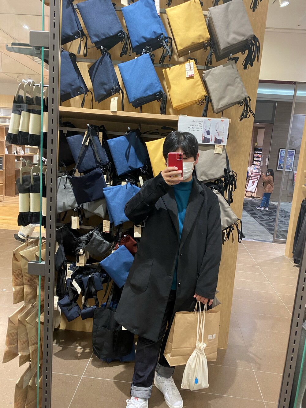 ブルー系のニット/セーター、ブラック系のジャケット/アウター、ベージュ系のバッグを着用したメンズの冬コーディネートの2枚目の写真