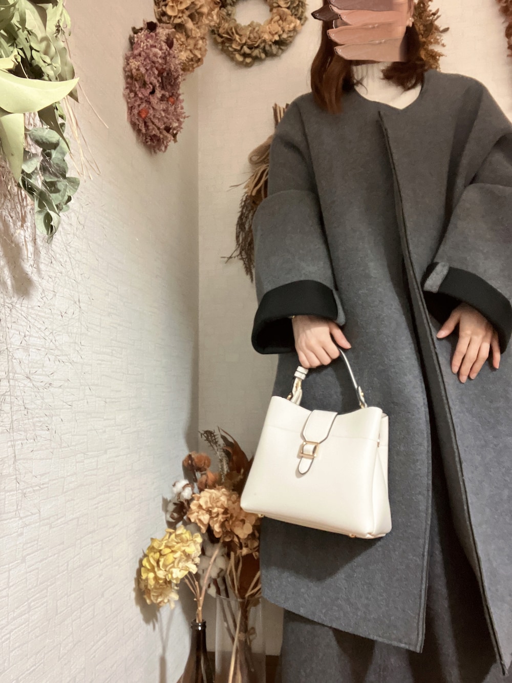 ホワイト系のハンドバッグ、ホワイト系のニット/セーター、グレー系のスカートを着用したレディースの冬コーディネートの2枚目の写真