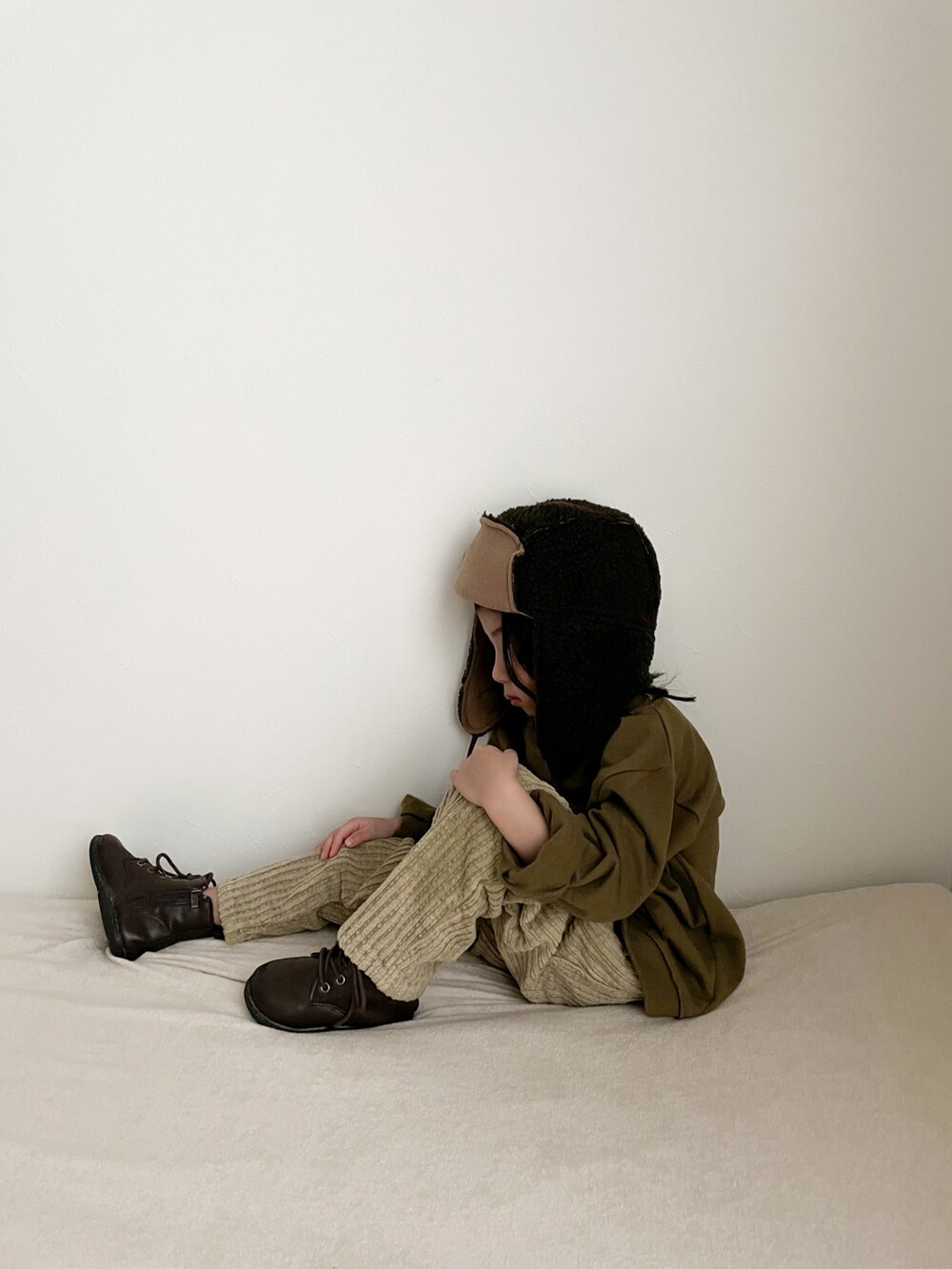 グリーン系のスウェット、ベージュ系のパンツ、ブラック系の帽子を着用したキッズの冬コーディネートの2枚目の写真