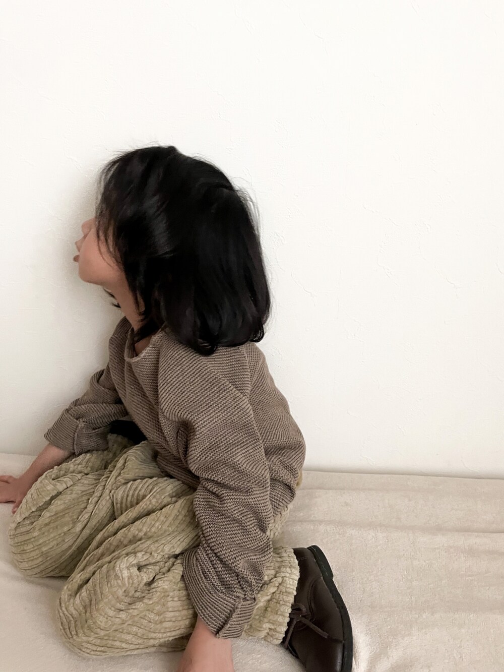 グリーン系のスウェット、ベージュ系のパンツ、ブラック系の帽子を着用したキッズの冬コーディネートの3枚目の写真