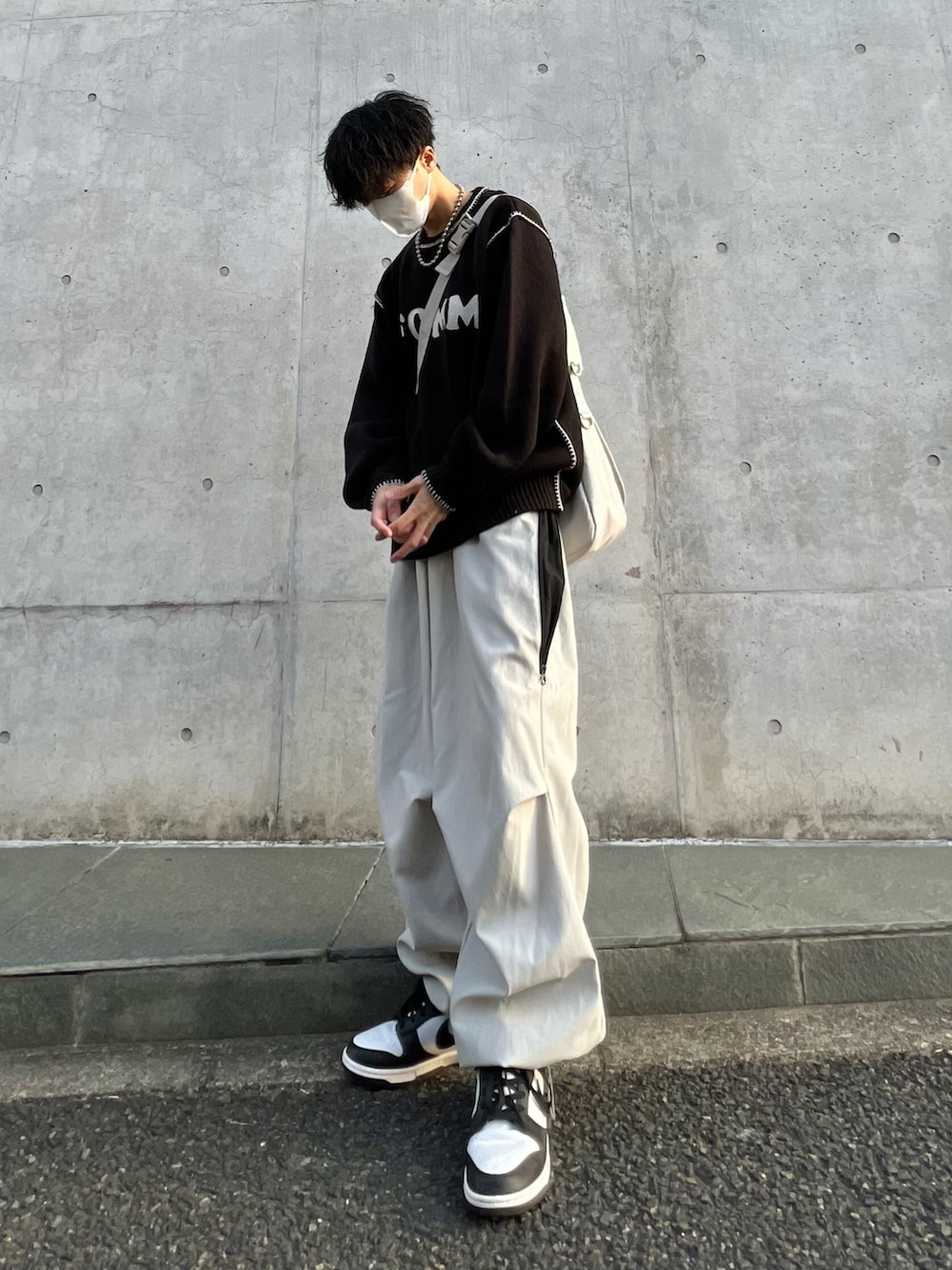ブラック系のニット/セーター、ホワイト系のカーゴパンツ、ブラック系のスニーカーを着用したメンズの春コーディネートの3枚目の写真