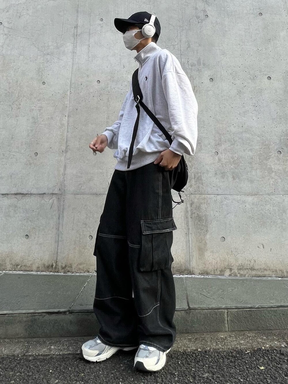 グレー系のトップス、ブラック系のデニムパンツ、ホワイト系のスニーカーを着用したメンズの冬コーディネートの2枚目の写真