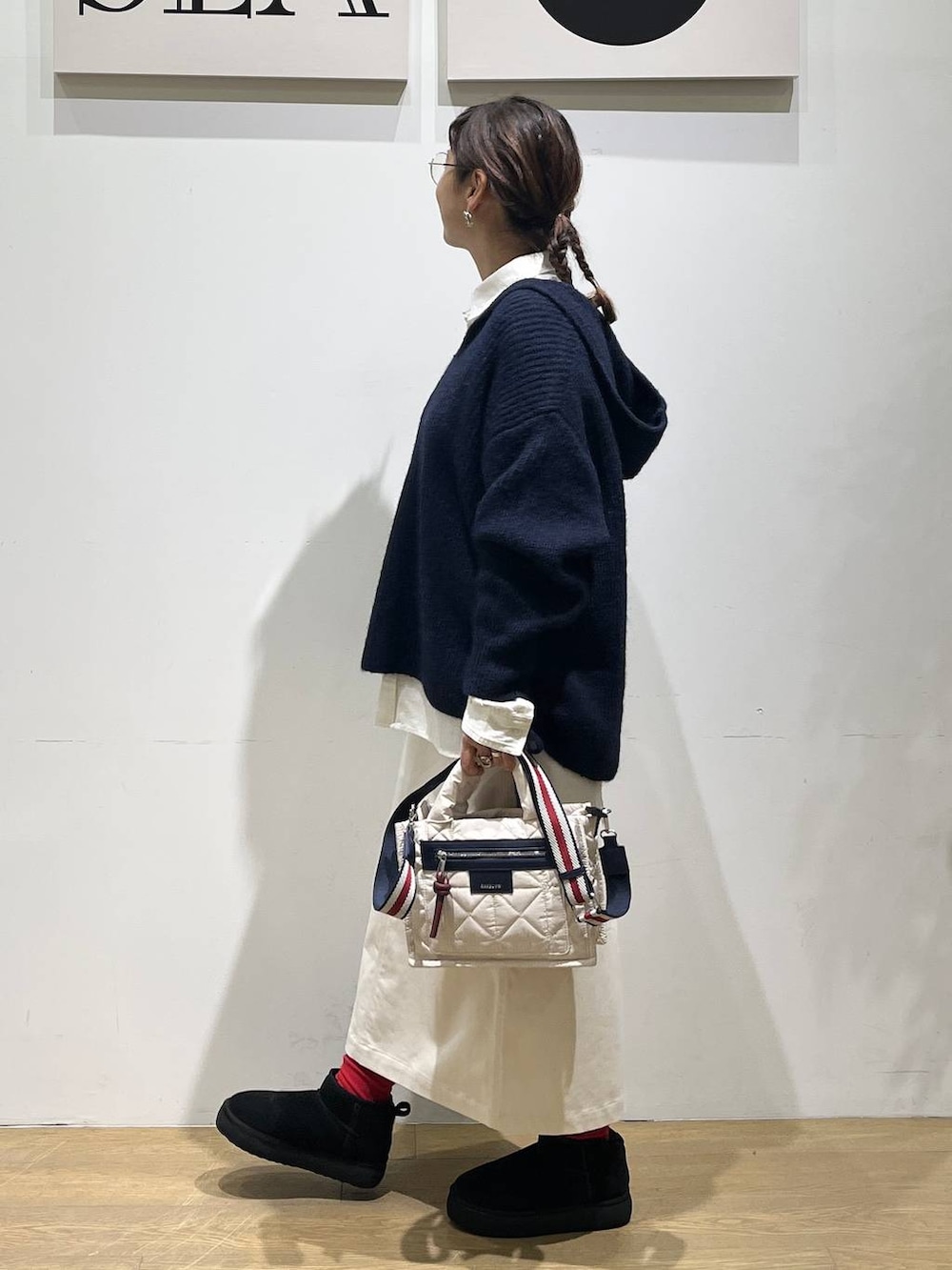 ホワイト系のショルダーバッグ、ベージュ系のスカート、ブラック系のブーツを着用したレディースの秋コーディネートの2枚目の写真