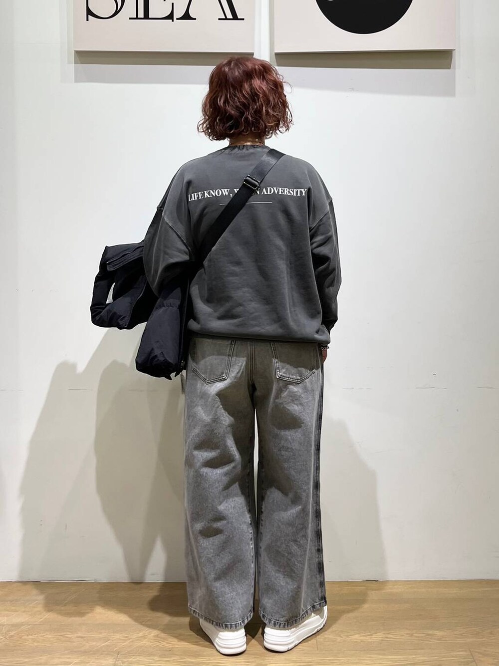 ホワイト系のスニーカー、グレー系のスウェット、ブラック系のショルダーバッグを着用したレディースの冬コーディネートの3枚目の写真