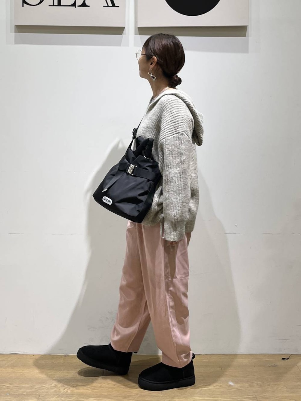 ブラック系のトートバッグ、ベージュ系のTシャツ/カットソー、ブラック系のブーツを着用したレディースの秋コーディネートの2枚目の写真