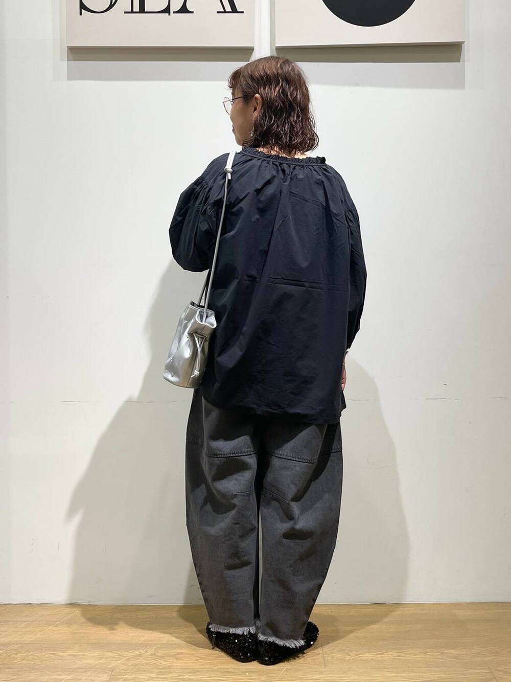 ブラック系のデニムパンツ、ブラック系のシャツ/ブラウス、シルバー系のショルダーバッグを着用したレディースの秋コーディネートの3枚目の写真