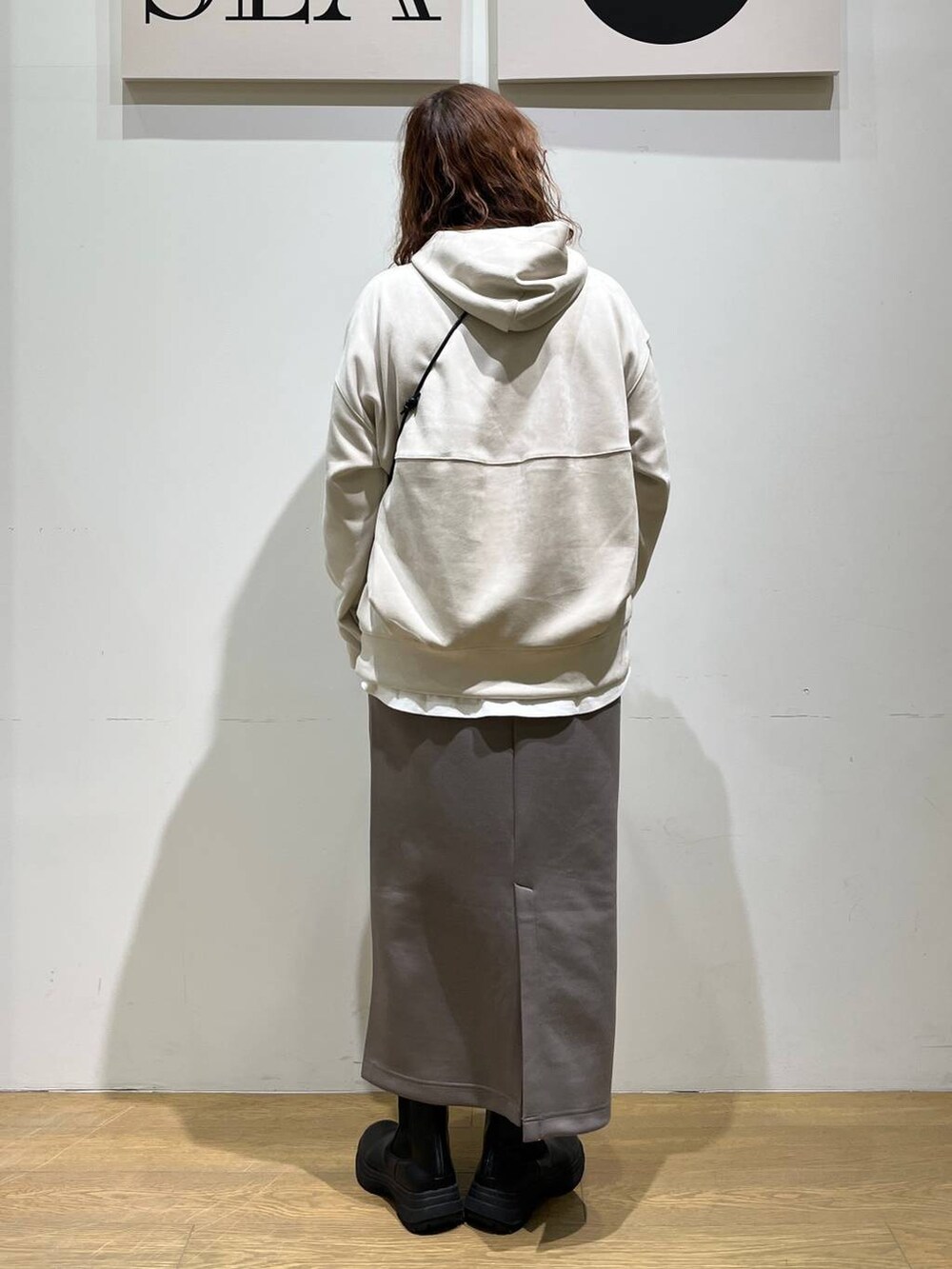 グレー系のショルダーバッグ、ホワイト系のTシャツ/カットソー、ブラック系のブーツを着用したレディースの冬コーディネートの3枚目の写真