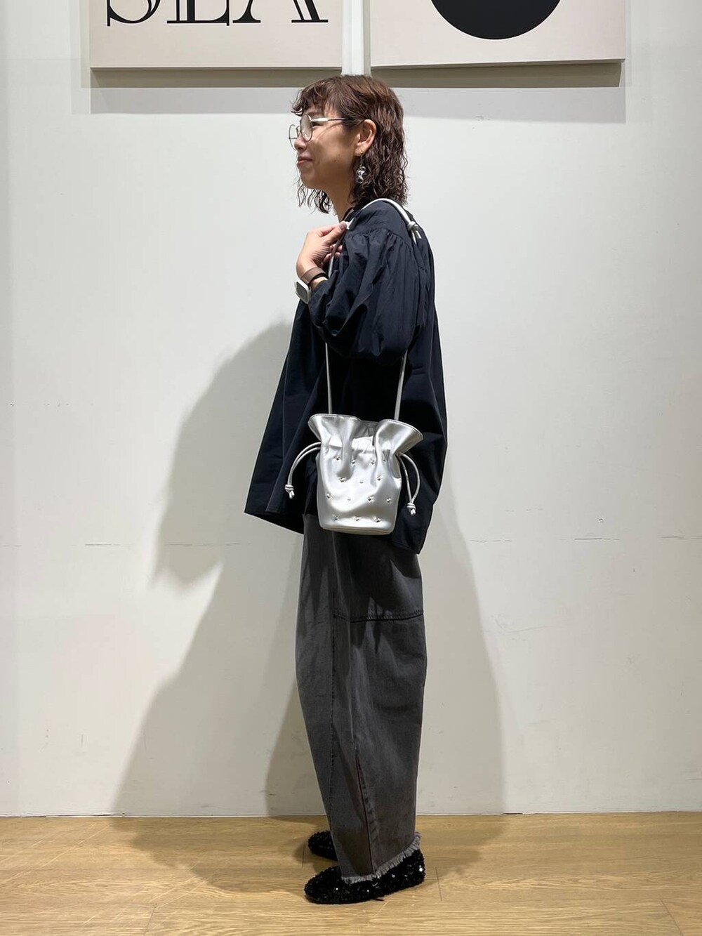ブラック系のデニムパンツ、ブラック系のシャツ/ブラウス、シルバー系のショルダーバッグを着用したレディースの秋コーディネートの2枚目の写真